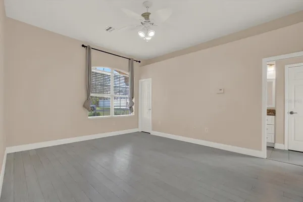 an empty room with wooden floor and windows with curtains
