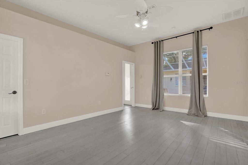 7190 Raymond Place Spring Hill, FL 34607 - Photo 27 of 41 an empty room with wooden floor and windows with curtains