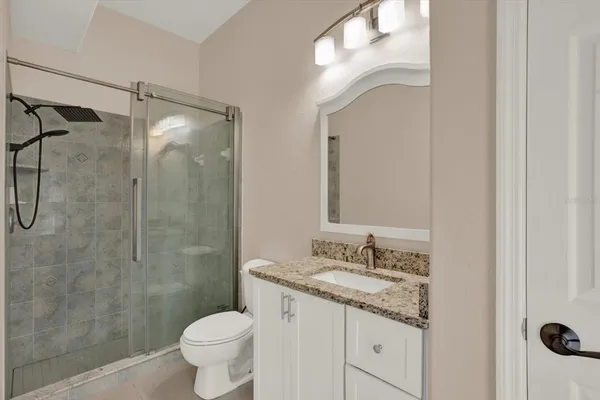 a bathroom with a granite countertop sink toilet a mirror and shower