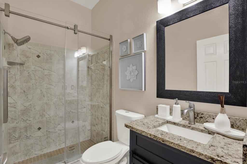 7190 Raymond Place Spring Hill, FL 34607 - Photo 29 of 41 a bathroom with a granite countertop sink toilet a mirror and shower