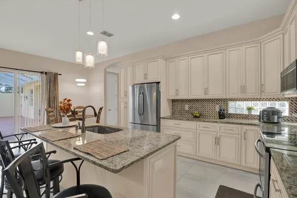 a kitchen with kitchen island granite countertop a sink cabinets and stainless steel appliances