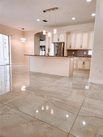 a large kitchen with stainless steel appliances kitchen island granite countertop a refrigerator a stove a sink and a black cabinets