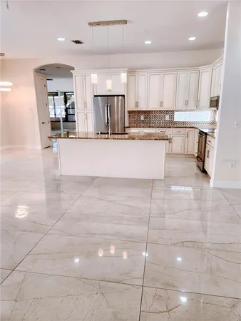 a large kitchen with kitchen island a stove a sink a counter top and cabinets