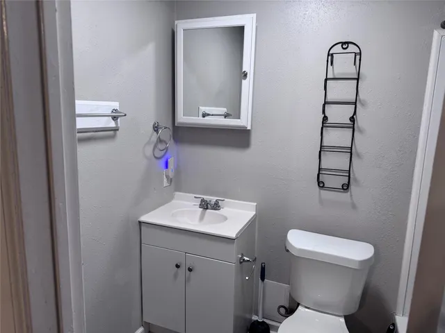 a bathroom with a toilet sink vanity and mirror