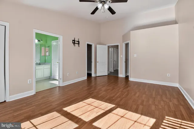 an empty room with wooden floor and ceiling fan