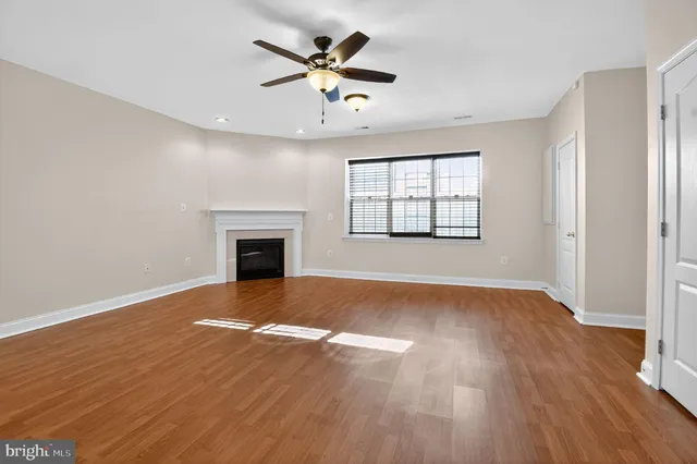 an empty room with wooden floor chandelier fan and windows