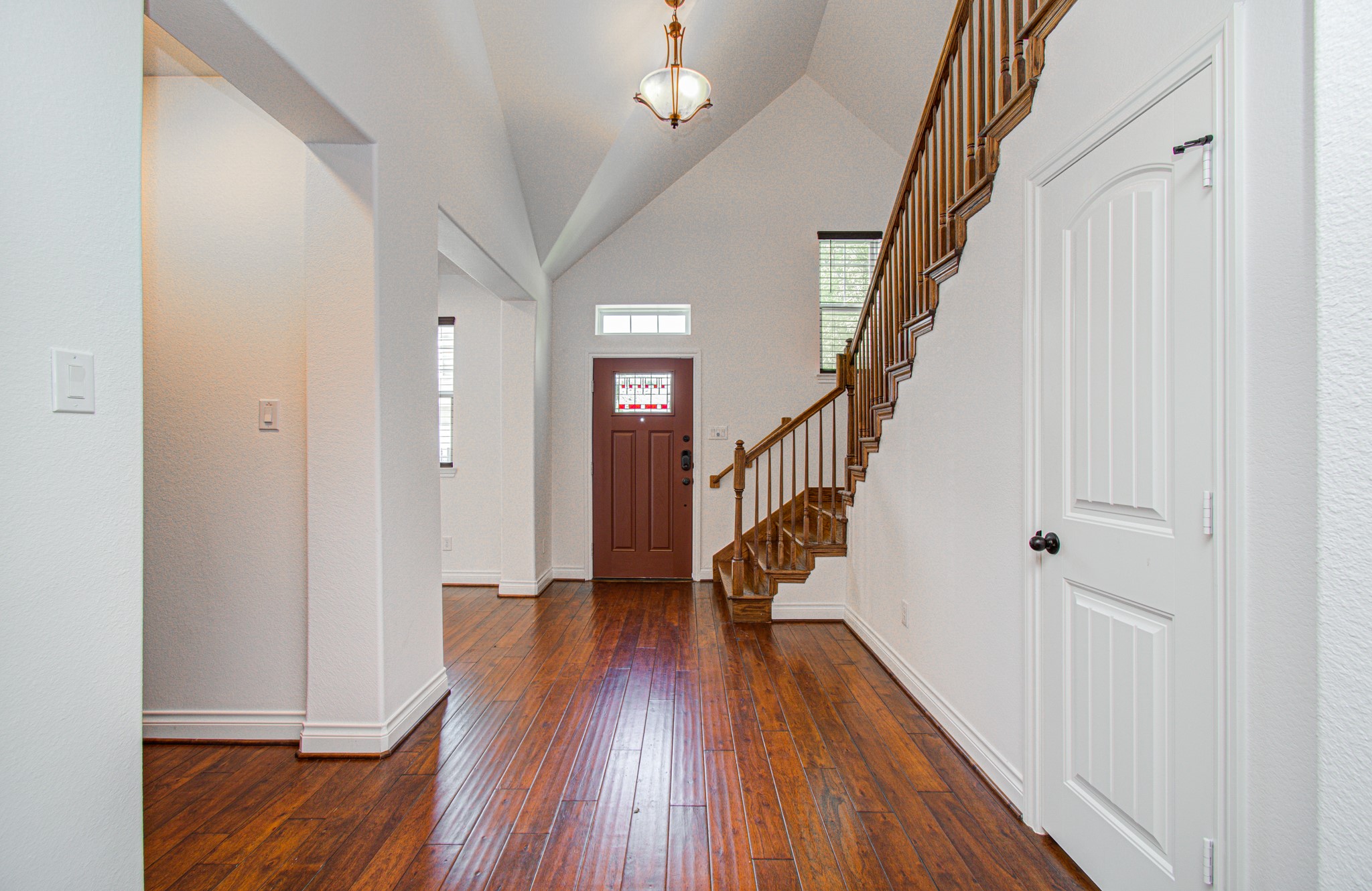6621 North Main Street Houston, TX 77009 - Photo 4 of 41 This photo showcases a bright and spacious entryway with high ceilings, elegant hardwood floors, and a beautiful wooden staircase. The area is illuminated by natural light through a window above the front door, creating a welcoming atmosphere.