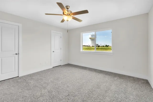 an empty room with a window and a ceiling fan
