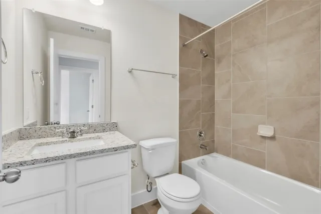 a bathroom with a granite countertop bathtub shower sink vanity mirror and toilet