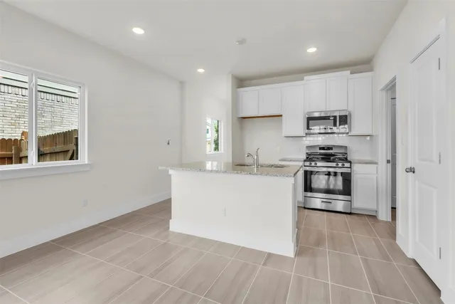 a kitchen with stainless steel appliances granite countertop a stove a sink and a refrigerator