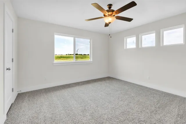 an empty room with a window and a ceiling fan