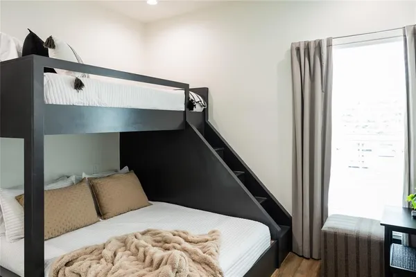 a bed sitting in a bedroom next to a window with wooden floor