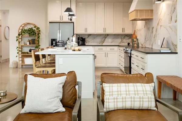 a kitchen with stainless steel appliances kitchen island granite countertop a table chair and a wooden floor