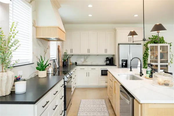 a kitchen with kitchen island granite countertop a sink a counter space appliances and cabinets