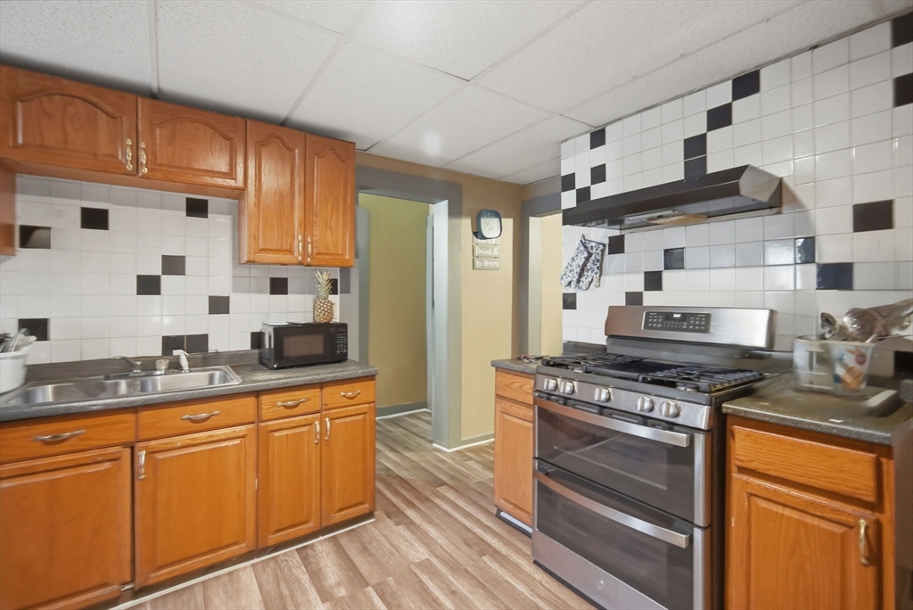 102-104 Cambridge Street Springfield, MA 01109 - Photo 11 of 38 a kitchen with stainless steel appliances granite countertop wooden cabinets stove top oven and sink