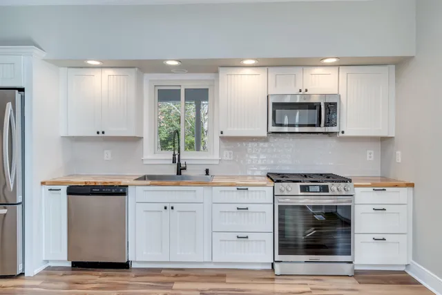 a kitchen with stainless steel appliances granite countertop a stove a sink and a microwave