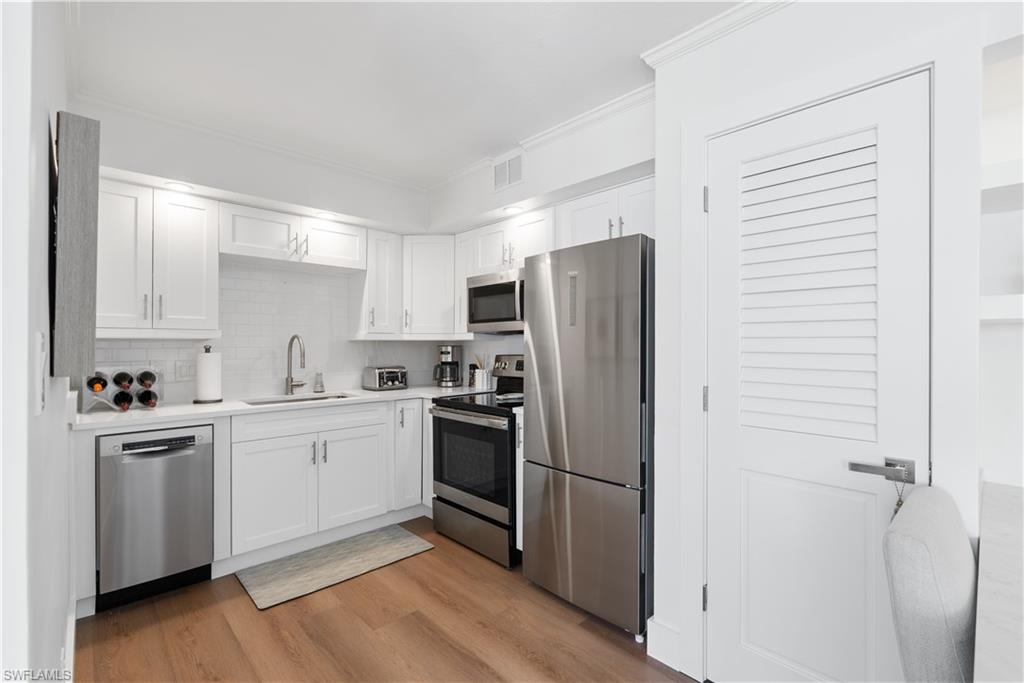 975 9th Avenue South, Unit 1 Naples, FL 34102 - Photo 26 of 34 a kitchen with a refrigerator stainless steel appliances wooden floor and cabinets