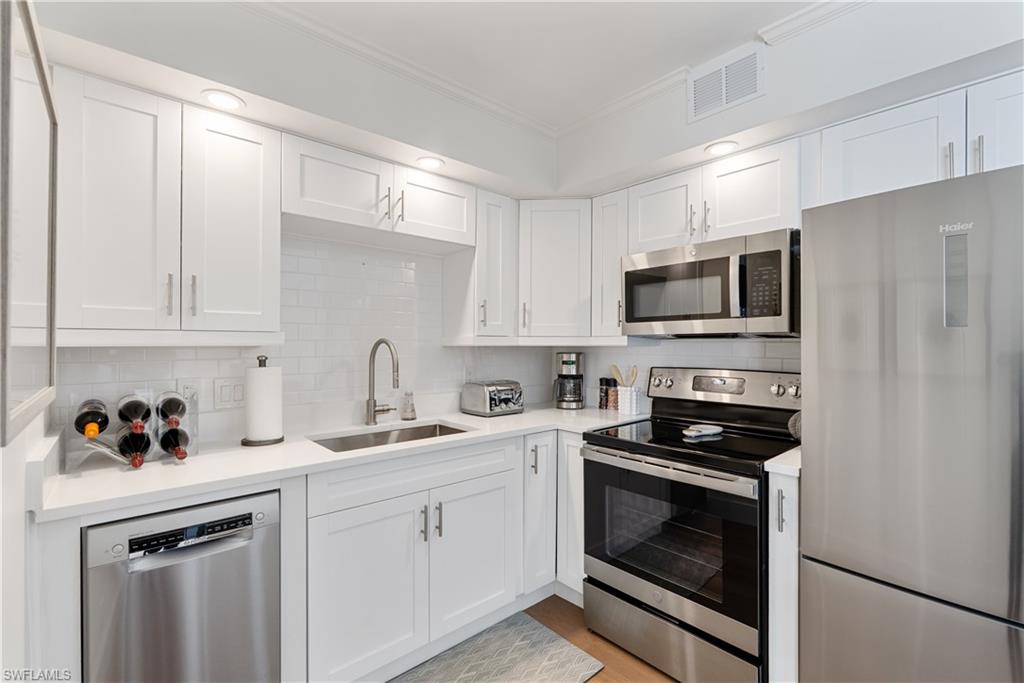 975 9th Avenue South, Unit 1 Naples, FL 34102 - Photo 27 of 34 a kitchen with white cabinets stainless steel appliances and sink