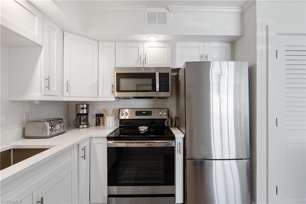 975 9th Avenue South, Unit 1 Naples, FL 34102 - Photo 28 of 34 a kitchen with refrigerator a microwave a sink and cabinets