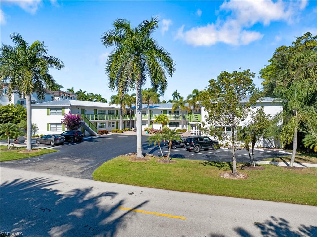 975 9th Avenue South, Unit 1 Naples, FL 34102 - Photo 10 of 34 a view of a swimming pool with a table and chairs under palm trees
