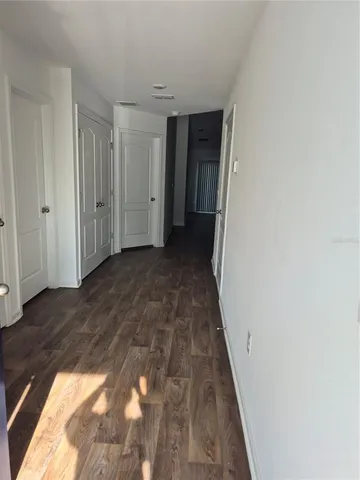 a view of a hallway with wooden floor and closet