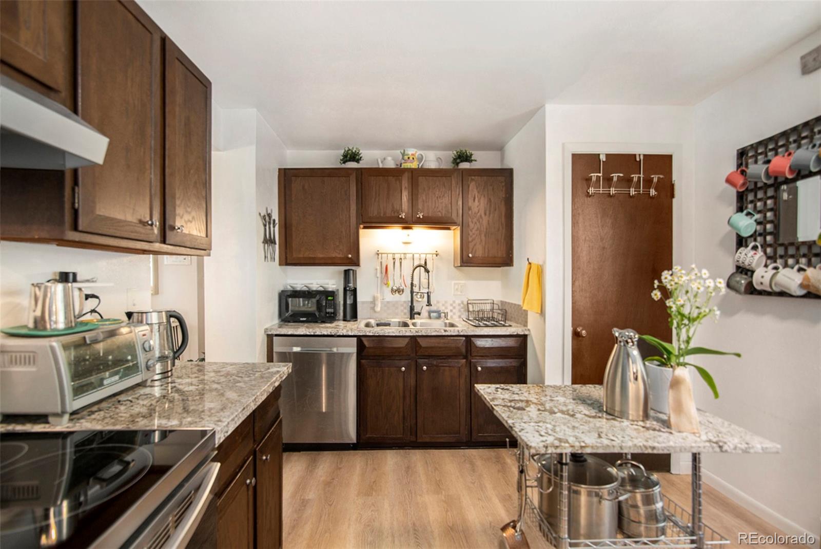 6180 South Ash Circle West Centennial, CO 80121 - Photo 7 of 23 a kitchen with granite countertop kitchen island stainless steel appliances a sink stove and cabinets