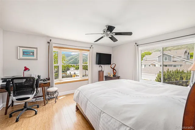 a bedroom with a bed and a large window with chair