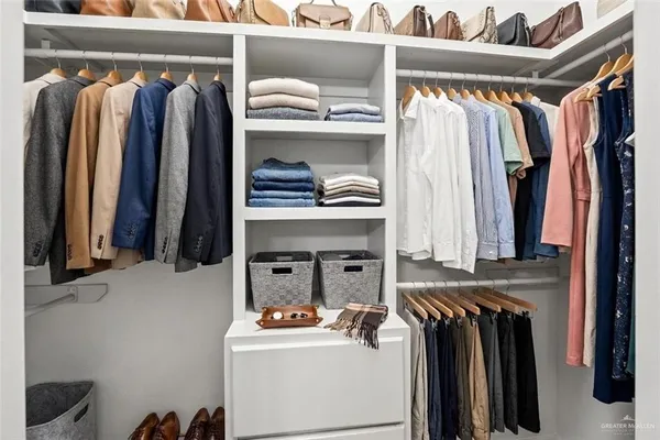 a view of walk in closet with clothes and shoes