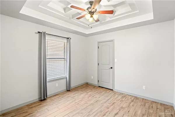 an empty room with wooden floor chandelier fan and windows