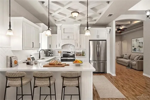 a kitchen with stainless steel appliances a stove a sink dishwasher a refrigerator with white cabinets and wooden floor