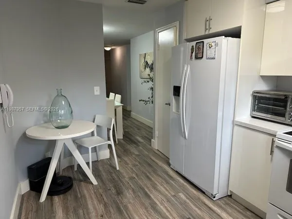 a kitchen with stainless steel appliances a refrigerator a sink a stove and white cabinets with wooden floor