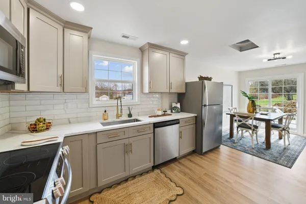 a kitchen with a sink a refrigerator a stove a dining table and chairs