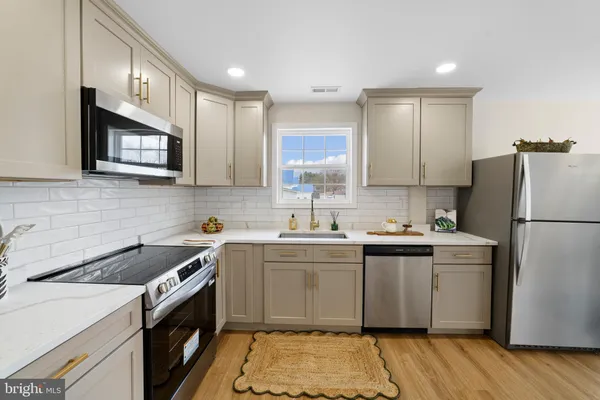 a kitchen with a sink a stove a refrigerator a microwave oven and cabinets