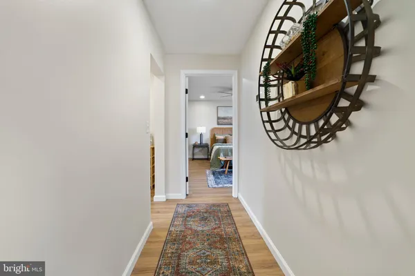 a view of a hallway with wooden floor and a bathroom