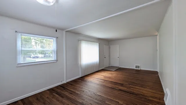 a view of an empty room with wooden floor and a window