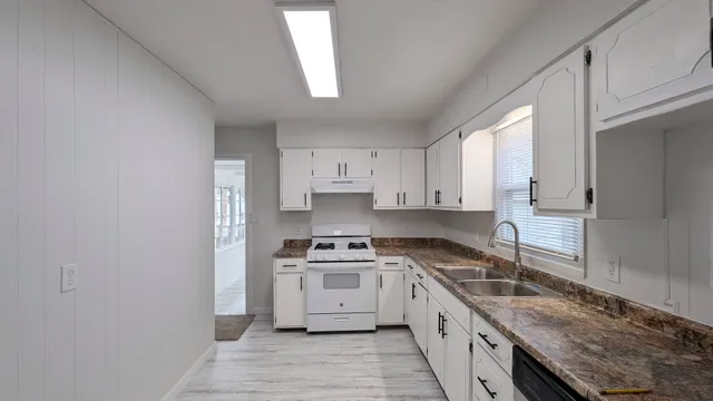 a kitchen with granite countertop white cabinets and white appliances