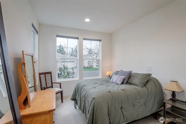 a bedroom with a bed wooden floor and a large window