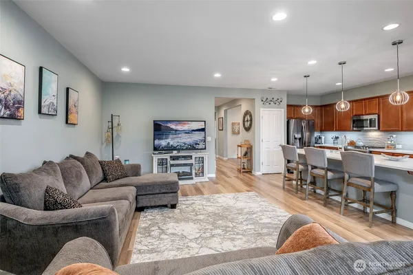 a living room with furniture kitchen view and a wooden floor