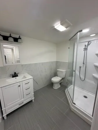 a bathroom with a double vanity sink a toilet and shower