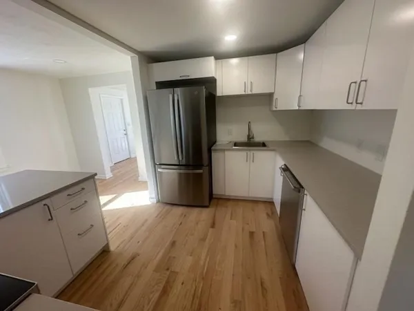 a kitchen with a refrigerator a sink wooden floor and cabinets