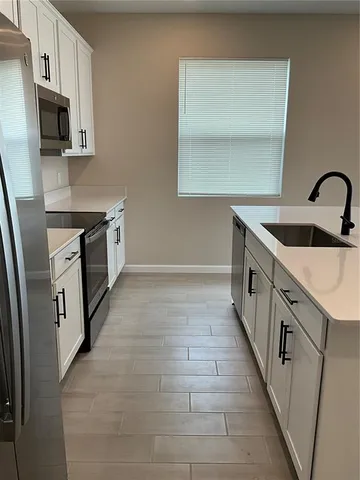 a kitchen with granite countertop a sink a stove top oven a refrigerator and cabinets