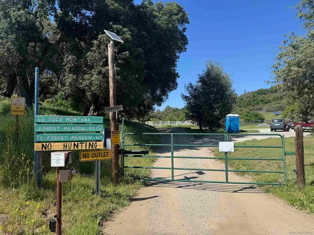 a view of a green field with trees in the background