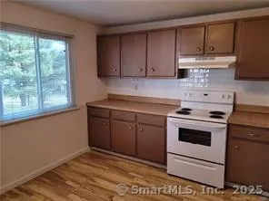 a kitchen with a stove white cabinetry and a sink