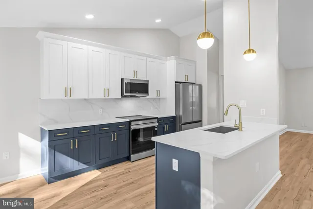 a kitchen with stainless steel appliances granite countertop a sink a stove a refrigerator cabinets and living room view