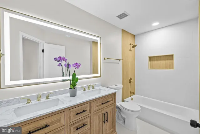 a bathroom with a granite countertop sink a toilet and a mirror