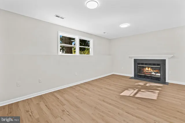 a view of empty room with wooden floor and fireplace