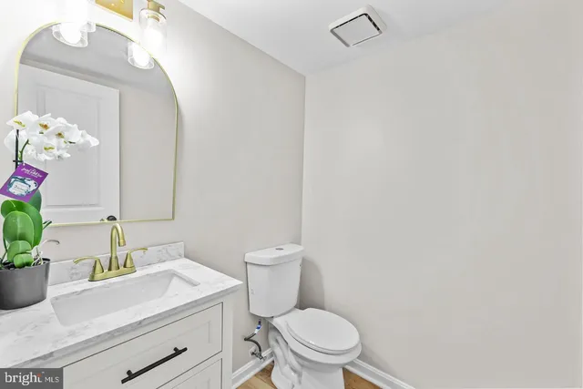 a bathroom with a granite countertop sink mirror vanity and toilet