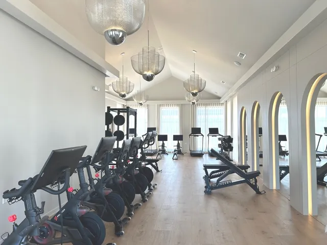 a room with lots of white furniture and chandelier
