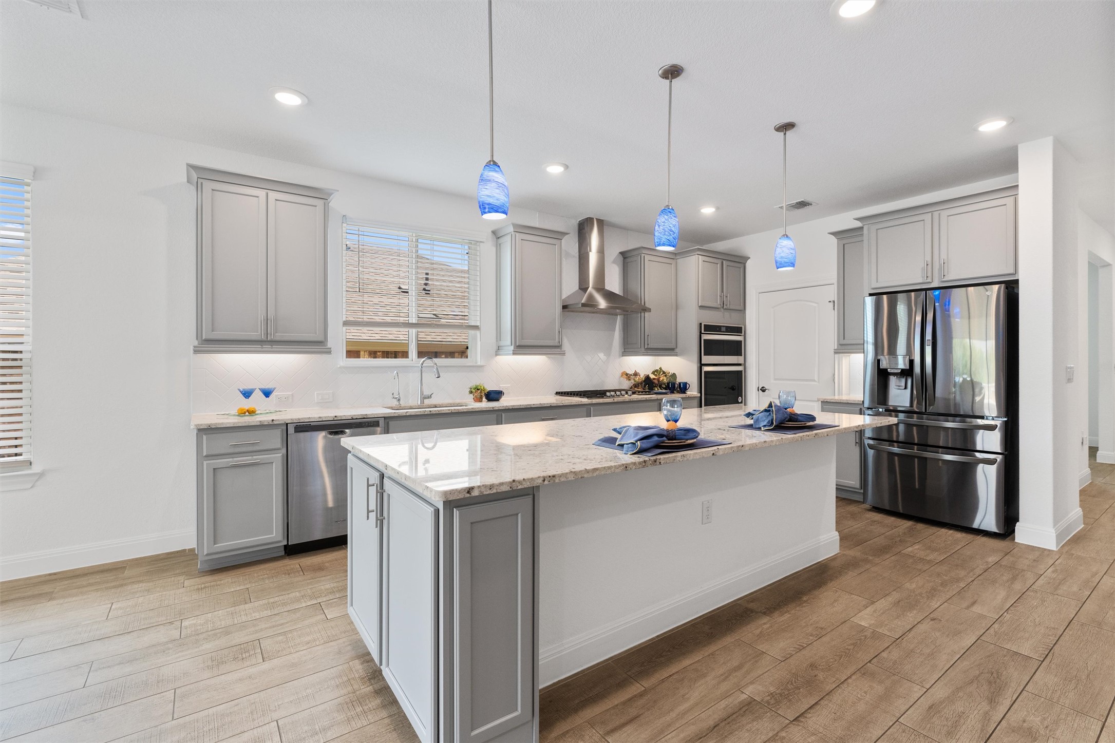 202 Spanish Star Street Georgetown, TX 78633 - Photo 9 of 32 a kitchen with stainless steel appliances granite countertop a sink a stove a refrigerator and island with wooden floor