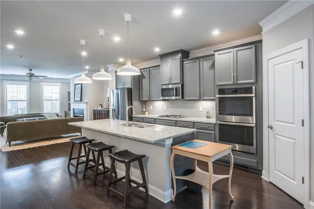a kitchen with stainless steel appliances granite countertop a stove refrigerator and a view of living room